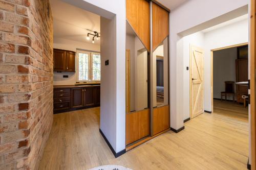 an open kitchen with wooden cabinets and a brick wall at Domek nad rzeką in Joniec