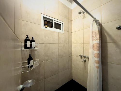 a bathroom with a shower with two bottles of wine at Tu casa en Ruta 34 - Wifi - Cochera -5 personas in Fernández