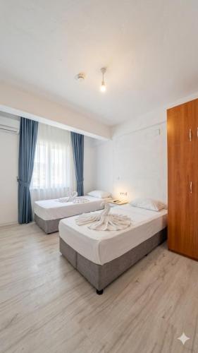 two beds in a large room with blue curtains at Mustafa Hotel Restaurant in Pamukkale