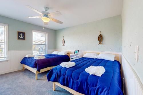 a bedroom with two beds and a ceiling fan at Maxs Nautical Nook Village OBX in Kitty Hawk