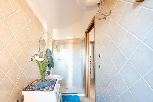 a bathroom with a toilet and a vase of flowers at Ri Ale Sa prassa Sardegna Ogliastra in Bari Sardo