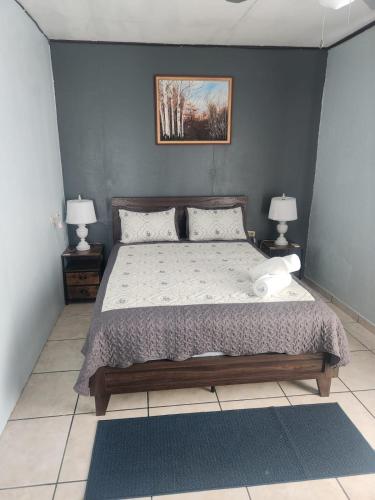 a bedroom with a bed and two night stands with lamps at Quepos Explorers Hub Spacious Apartment in Quepos