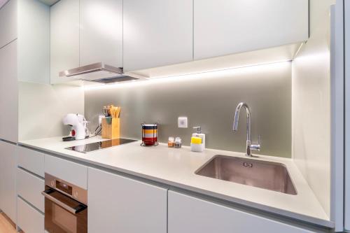 a kitchen with white cabinets and a sink at Leiria Boutique Apartment in Leiria
