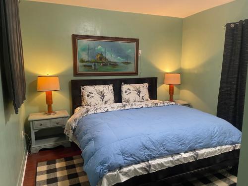a bedroom with a bed with blue sheets and two lamps at BACK HOUSE in PASADENA in Pasadena