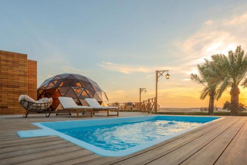 a deck with a swimming pool and a gazebo at Al Marmoom Oasis Luxury Experiential Desert Domes in Dubai