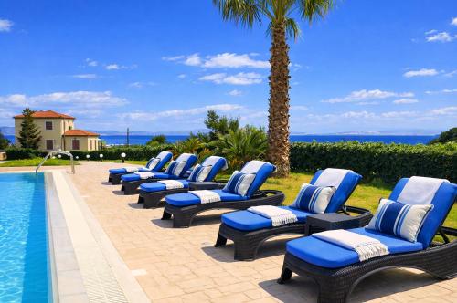 a row of chaise lounge chairs next to a swimming pool at Bella Villa with Private Pool & Sea View Ideal for Groups in Vaia