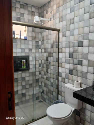 a bathroom with a toilet and a glass shower at Casa PA parque das aguas in Bonito
