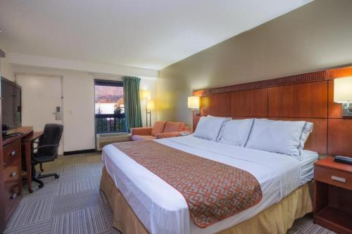 ein Hotelzimmer mit einem großen Bett und einem Schreibtisch in der Unterkunft Nations Inn - West Jefferson in West Jefferson