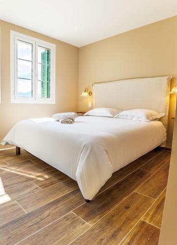 a large white bed in a bedroom with wooden floors at Juliette in Venaco