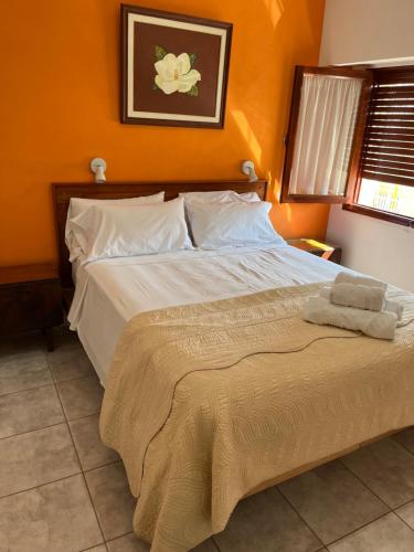 a bedroom with a large bed with an orange wall at El Buen Descanso in Gualeguaychú