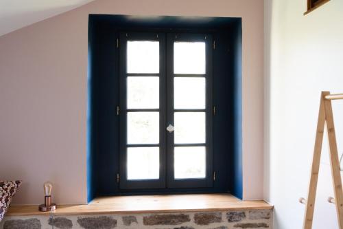 a black door with a window in a room at Le petit ordinaire in Le Cours