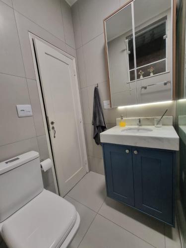 a bathroom with a toilet and a sink and a mirror at House Brigadeiro in Juiz de Fora