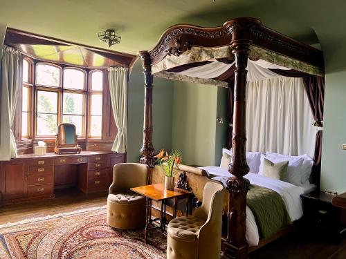 a bedroom with a canopy bed and a table and a chair at East Dene Estate in Ventnor