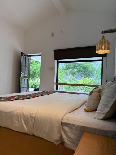 a bedroom with a large bed with a large window at Sukoon in Nainital