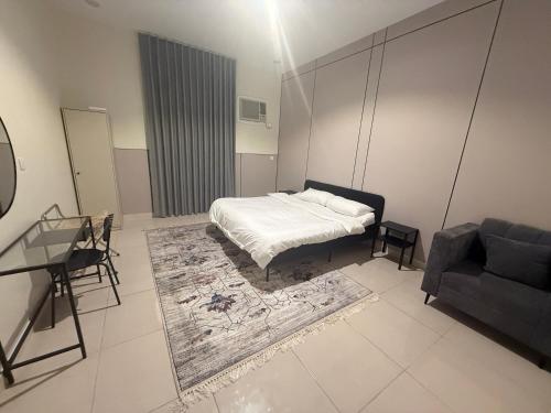 a bedroom with a bed and a table and a couch at استديو كلاود in Al Baha