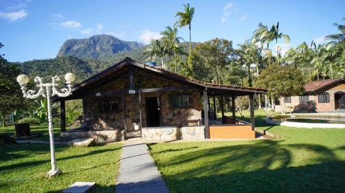 a small building with a mountain in the background at Chácara bello Rio in Guaratuba