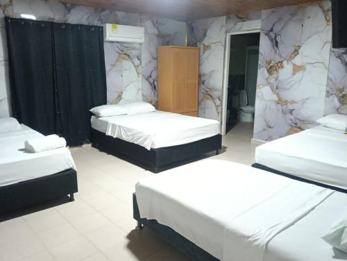 a room with three beds and a marble wall at Hostal Dream House in San Andrés