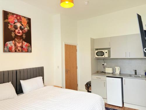 a small bedroom with a bed and a kitchen at Stylish Studio flat 5, ensuite, kitchenette, Wifi,Parking,Smart TV,Contractors,NHS,Families welcome in West Bromwich