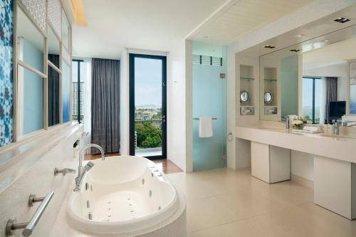 a bathroom with a tub and a sink and a mirror at Amari Pattaya in Pattaya