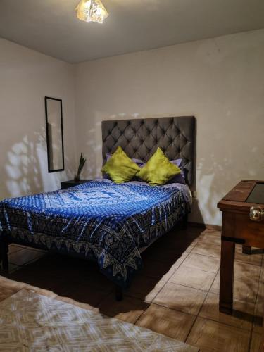 sypialnia z łóżkiem z niebieską kołdrą i żółtymi poduszkami w obiekcie Apartment 2 w mieście Santa María Tonantzintla