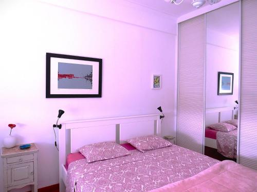 a bedroom with pink walls and a bed and a mirror at Al-Madan in Almada