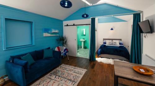 a blue bedroom with a bed and a couch at Skye Blue Bothy in Teangue