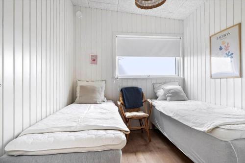 two beds in a room with a window and a chair at 20428-Samso-Radyrvej-10 in Langemark