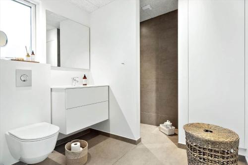 a white bathroom with a toilet and a sink at 20428-Samso-Radyrvej-10 in Langemark