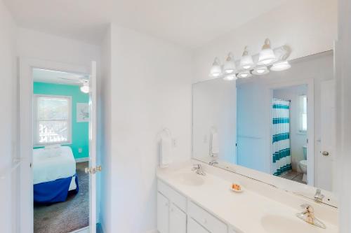 a white bathroom with a sink and a mirror at Sandcastle in Corolla