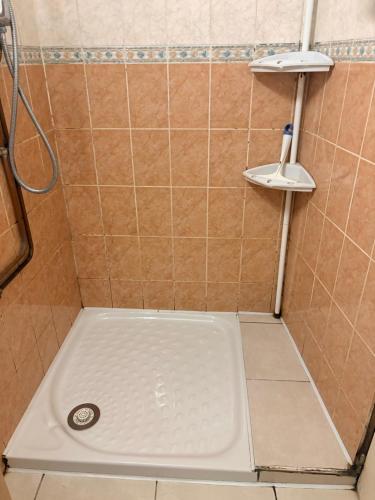 a shower with a white floor and a tile wall at A room and garden close to Paris in Vitry-sur-Seine