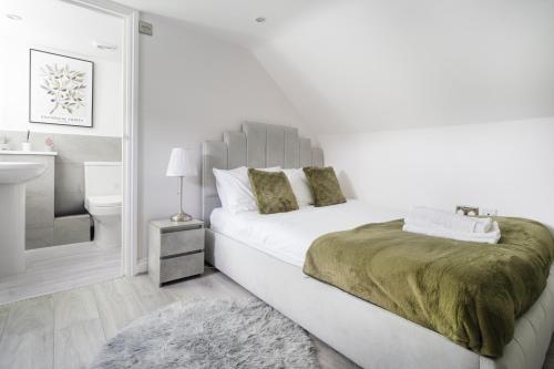 a white bedroom with a bed and a sink at Jasmin Place in Luton