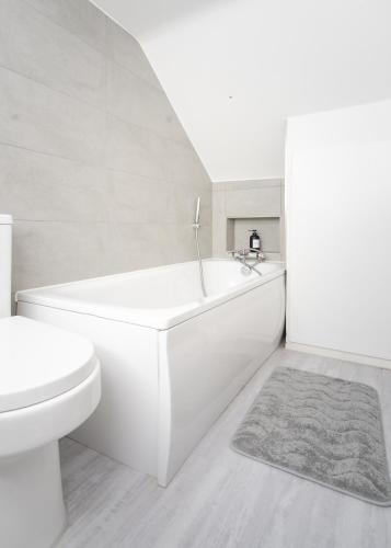 a white bathroom with a tub and a toilet at Jasmin Place in Luton