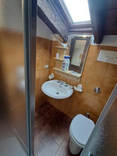 a bathroom with a sink and a toilet and a mirror at Casa tra i boschi in Esino Lario