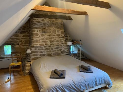 a bedroom with a bed and a stone wall at La maison de Jeanne La Monédière in Chaumeil