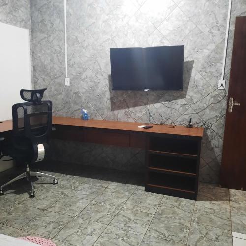 a desk with a chair and a television on a wall at Apartamento confortável em Cuiabá in Cuiabá