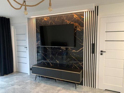 a living room with a television on a wall at Mazury Apartamenty wodne tarasy Blue - Ruś in Ruś