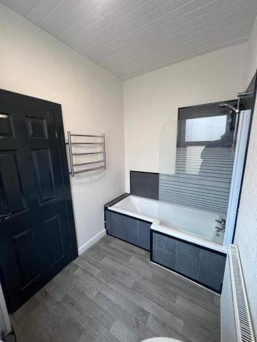 a bathroom with a bath tub and a black door at ONYX Hotel Blackpool in Blackpool