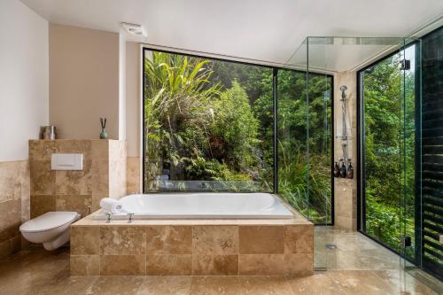 a bathroom with a tub and a toilet and a large window at The Point Villas in Taupo