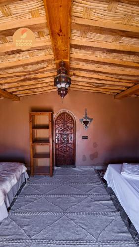a room with two beds and a wooden ceiling at Mhamid Auberge Saharaespace in Mhamid