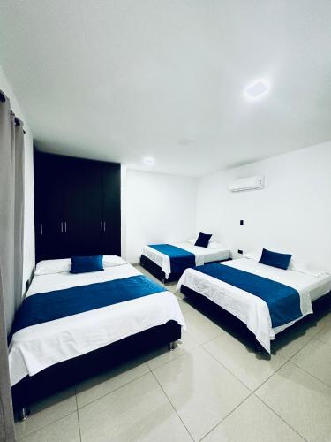 a bedroom with two beds with blue and white sheets at Hotel Barcelona in Montería