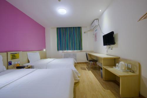 Conghuaにある7Days Inn Guangzhou Conghua Street Hedongのベッド2台とデスクが備わるホテルルームです。