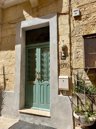 a green door on a building with a stone wall at Dar Divinus - Eat, Wine, Sleep in Rabat