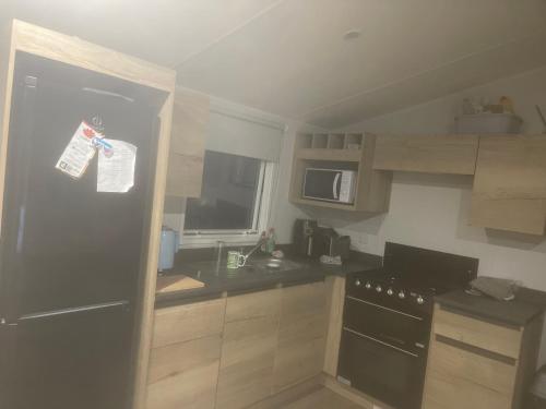 a kitchen with a black refrigerator and a microwave at Neal 6 berth static rental in Skegness