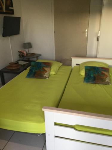 a bedroom with two beds with green sheets at studio Rony in Port-Louis