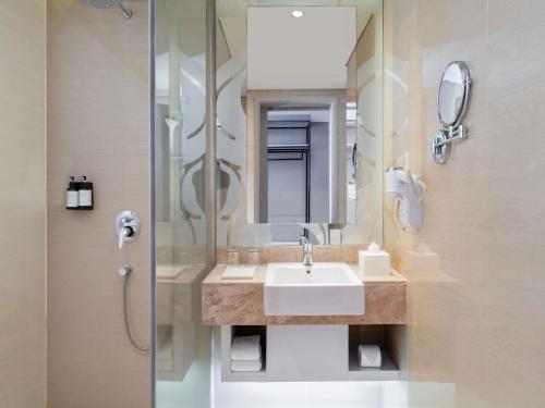 a bathroom with a sink and a shower at Mercure Jakarta Sabang in Jakarta