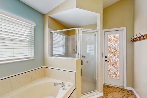 a bathroom with a tub and a shower and a window at Sebastian Serenity in Sebastian