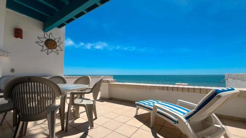 a balcony with a table and chairs and the ocean at Warm & Charming Beachfront Condo Las Olas II 8 in Puerto Peñasco