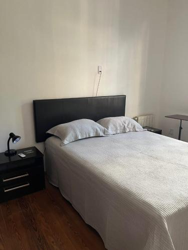 a bedroom with a white bed with a black headboard at Casa en Pocitos in Montevideo