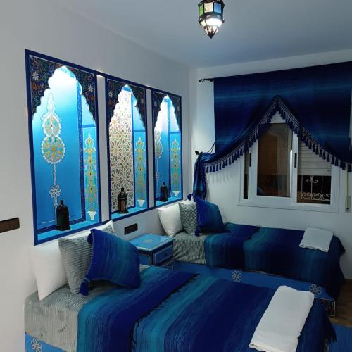a blue bedroom with two beds and a window at Dar Achraf in Chefchaouen