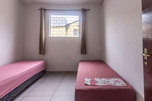 a small room with two beds and a window at Apto para 8 pessoas com Garagem e Churrasqueira in Pará de Minas